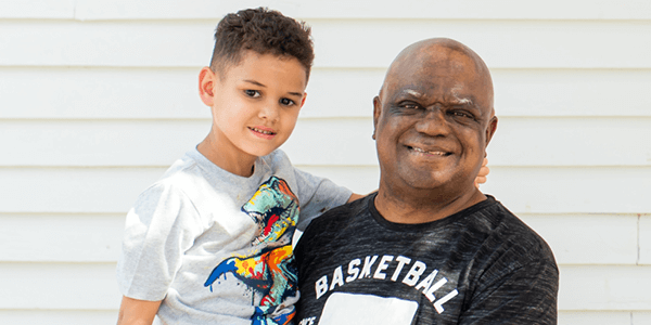 An adult holding a child, both looking at the camera